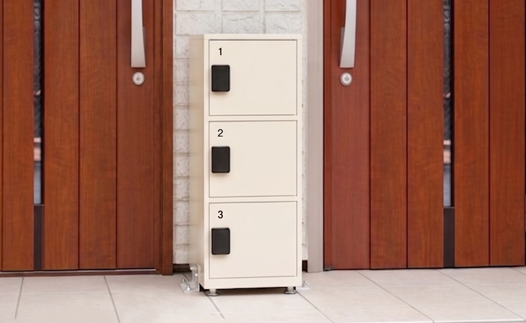 住宅の玄関ポーチに、縦に3段並んだ宅配ボックスが設置され、木目調の玄関ドアと壁付けポストが並ぶすっきりした外観